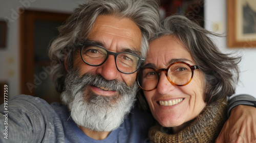 A gray-haired couple with wonderful cheerful smiles and sincerity takes a selfie on their phone. Today's active retirees are enjoying life. The man has a gray beard. and a woman wearing glasses,