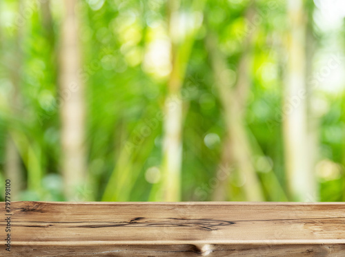 Empty wooden board or table top and blurred green bamboo culms. Place for your product display.