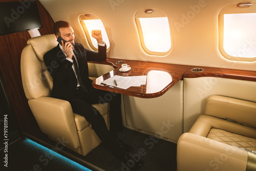 Businessman wearing corporate business suit flying on luxury private jet, concepts about travel, transportation and wealthy lifestyle