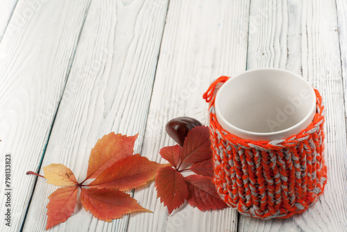 Autumn still life cup of coffee on wooden table. nitted sweater with autumn leaves, spokes, crochet and coffee mug. Autumn moody style background. Top view.