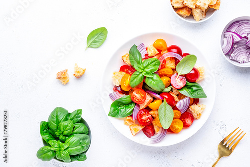 Summer italian salad with stale bread, tomatoes, red onion, olive oil, salt and green basil, white table background, top view