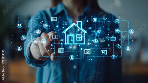 Smart Home Interface: Businesswoman in denim shirt uses a transparent digital interface, pointing at a house icon, indicating interaction with real estate or home automation systems.