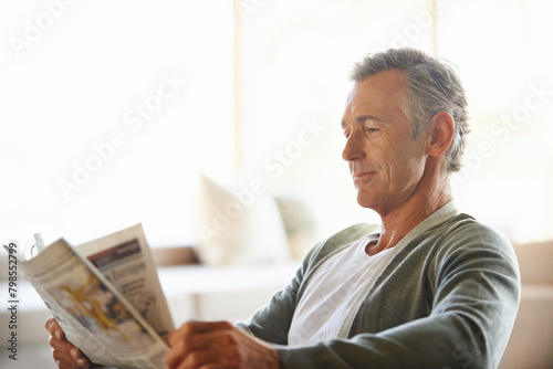 Mature, man and newspaper for reading in home, relax and information or articles in morning with coffee. News, breakfast table and rest and calm for entertainment pages, current events in apartment