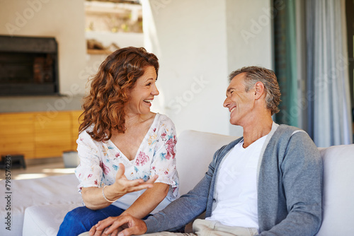 Laughing, happy or mature couple in home living room for conversation or communication in marriage. Smile, talking or funny woman speaking of joke to man in retirement or discussion to relax together