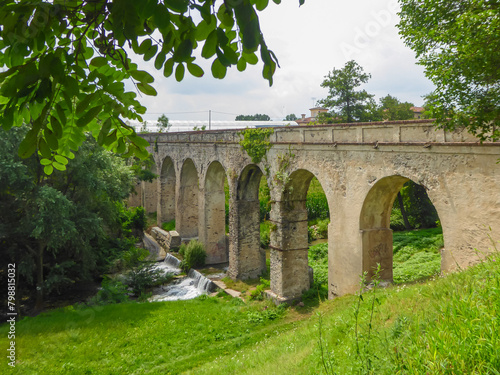 Panoramic view of hidden unknown ancient old Roman Aqueduct Ponte Aquedotto del 1700 - 1734 in the village of Busca, Cuneo province, Piedmont, Italy. Seen from a dense forest. Used as pedestrian rood