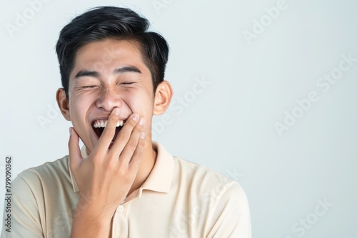 Happily laughing young man in a studio listening to a joke in discussion. Happy, funny, handsome Indian man with goofy or stupid demeanor from white background