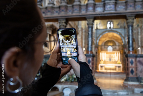 A female tourist taking photos with phone inside the Basilica di San Marco (Saint Mark's Basilica) in Venice; Italy