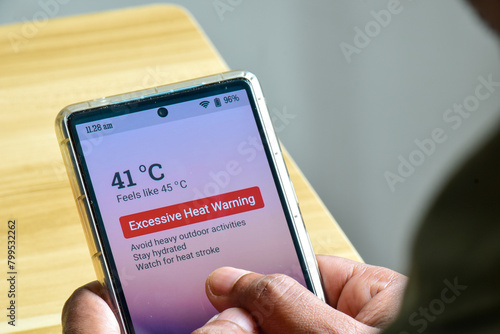 Man using his mobile phone displaying alertness for excessive heat warning. Severe weather El Nino condition.