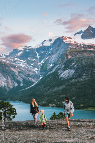 Family walking outdoor traveling together in Norway - mother, father and child on summer vacation hiking adventure active trip healthy lifestyle parents with kid enjoying fjord and mountains landscape