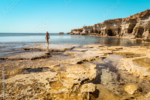 Tourist woman stand on rocky formations by sea cave in Ayia Napa, Cyprus. A shot from the inside of a sea cave in sunny Mediterranean coast of greek Cyprus. Grotto sea cave swim