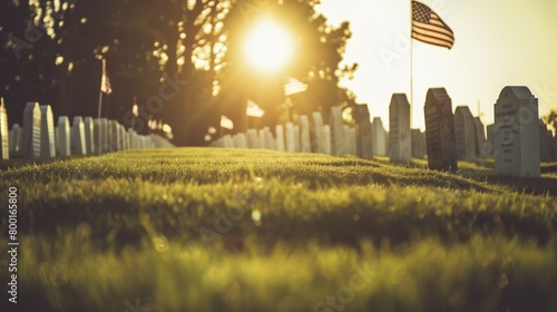 The sun sets over a cemetery, casting a golden light on the grass and American flag in the foreground, creating a peaceful natural landscape