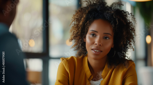 A photograph of a biracial woman engaging in a dynamic conversation with interviewers