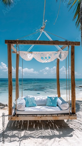 wooden swing with a mattress and pillows under a canopy on the tropical beach
