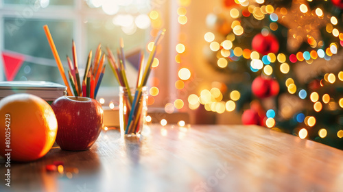 Bright and warm holiday photo. Table with school supplies, colored pencils, apple and orange. A Christmas tree with glowing lights is depicted on a blurred background