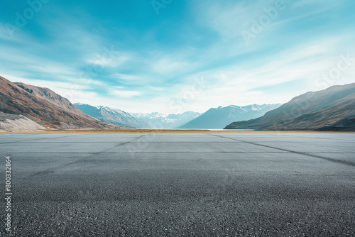 Empty asphalt under a blue sky and rolling mountains in the distance