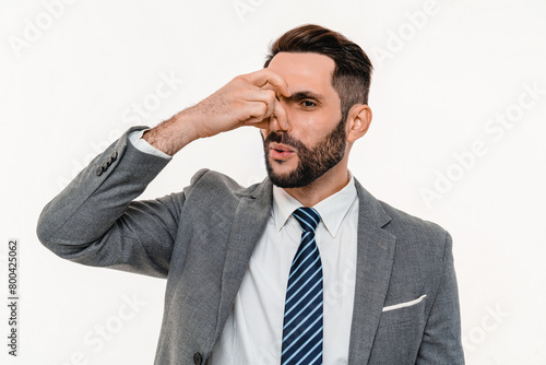 Displeased young businessman pinching his nose because of strong odor isolated over white background. The smell of sweat, fart, spoiled rotten food meal, stinky socks