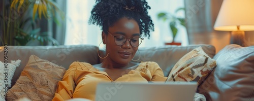Mature Black woman on computer at home on sofa connecting