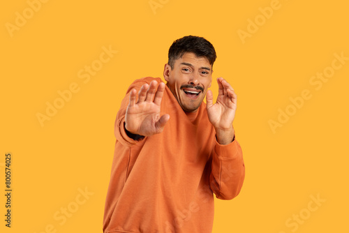 Man in Orange Shirt Making Hand Gesture
