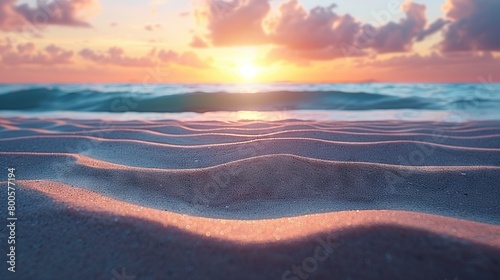 The sun is setting over the ocean on a beach with sand blowing in the foreground and waves lapping at the shore in the background