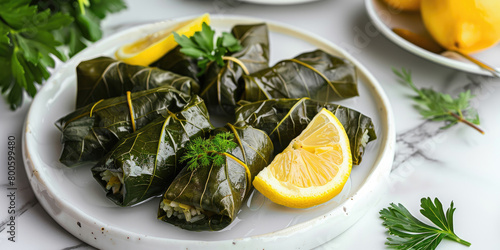 Dolma served on a white quartz background, Grape leaves stuffed with seasoned rice and herbs, Garnished with lemon wedges, turkish food