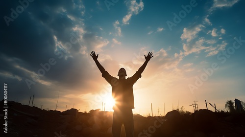 silhouette of praying person raising his hands to the sky outdoors