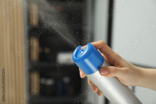 Woman spraying air freshener at home, closeup. Space for text