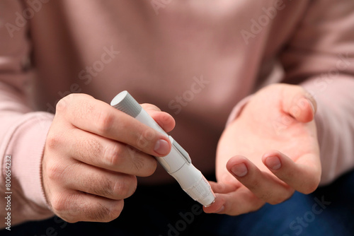 Diabetes test. Man checking blood sugar level with lancet pen, closeup