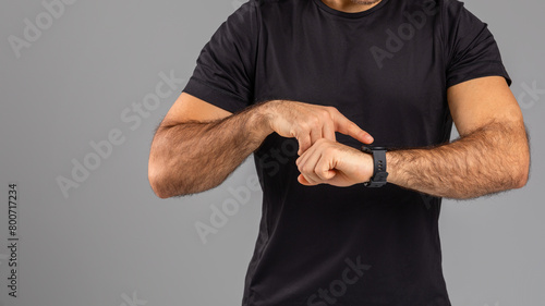 Man Checking Time on Wristwatch Against Gray Background