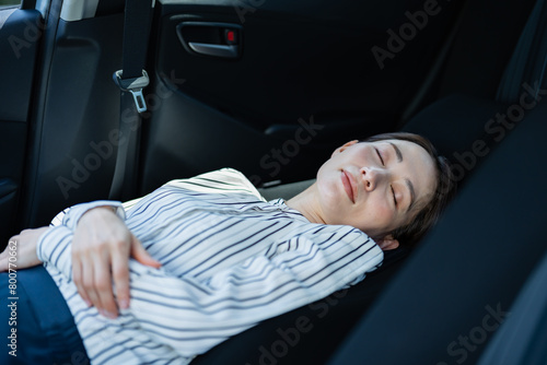 運転席を倒して車内で寝る女性
