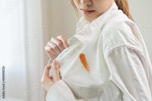 Dirty sauce stain cloth, asian young woman, girl wearing white shirt showing making on her cloth stain, spot dirty or smudge on clothes for cleaning before washing, maid female working at home concept