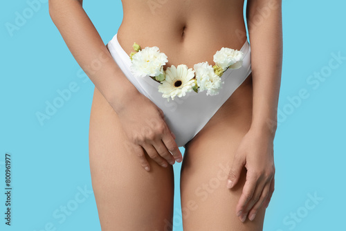Beautiful young woman in panties with gerbera flowers on blue background, closeup