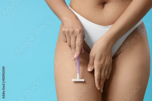 Beautiful young woman with razor on blue background. Depilation concept