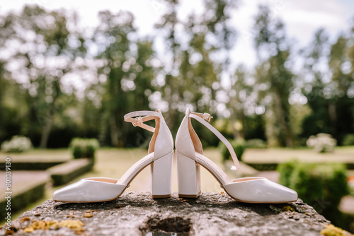 Valmiera, Latvia - August 19, 2023 - Wedding shoes on a stone wall, positioned with the park's greenery in the soft-focus background.