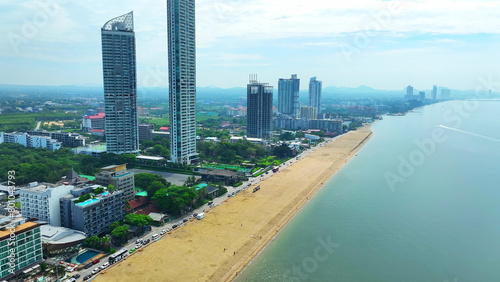 Crystal-clear turquoise waters caress the golden sands, while elegant coastal buildings stand tall, creating a picturesque backdrop. Iconic landmarks draw tourists globally. Jomtien Beach, Thailand. 