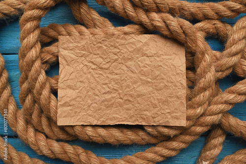 Empty blank letter page sheet and moorings rope on the blue table background. Columbus day concept.