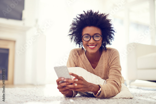 Black woman, portrait and afro with phone on living room floor for social media, blog or reading news at home. African, female person or freelancer on mobile smartphone for communication at house