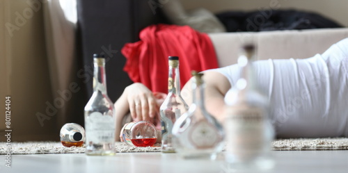 Portrait of male napping after rough night party. Male drunkard sleeping on comfortable sofa and holding bottle of expensive alcohol. Consequences of irresponsible drinking concept