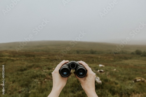 Bird watcher holding binoculars in Scottish Highlands