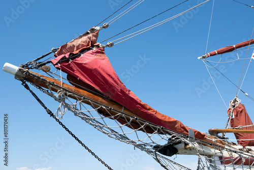 Ship's bow with jib boom and knotted jib net in front of the foremast of a moored sailing ship, stretched between the two bow stays at blue sky