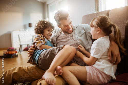 Happy father playing with son and daughter at home