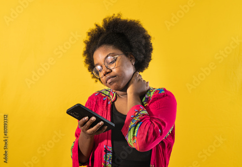 Una mujer afroamericana usando teléfono celular en la mano y disfrutando de aplicaciones sobre fondo amarillo
