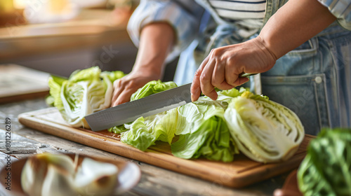 Woman cutting fresh chinese cabbage on table closeup -