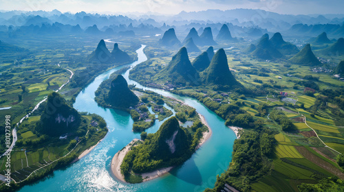  an aerial shot of the Li River in China. The river winds its way through the green and misty mountains. There are small villages and boats on the river.