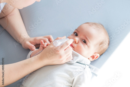 Mother using baby nasal aspirator mucus nose suction. Mother cleaning baby nose. Baby watching to camera.