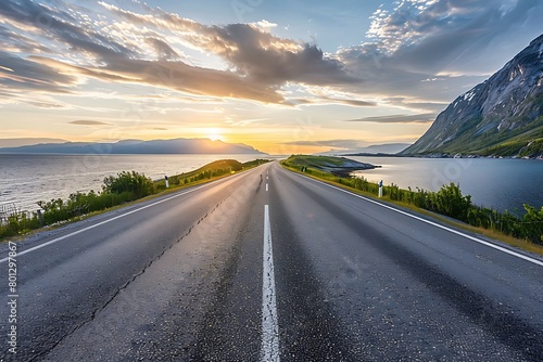A coastal road in Norway, with the sea on one side and cliffs to another, bathed by the golden sunset light