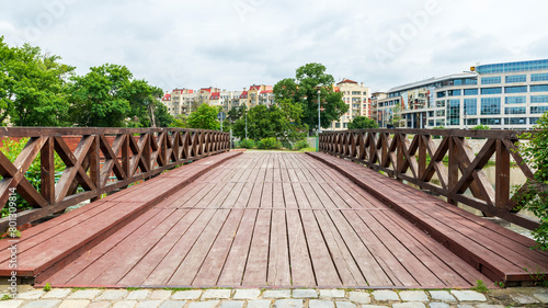Old wooden pedestrian and bicycle bridge in the central part of Wrocław, Poland. A big contrast to the newer tall brick buildings in the background.