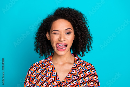 Photo of charming flirty lady wear print shirt licking lios stick out winking eye empty space isolated blue color background