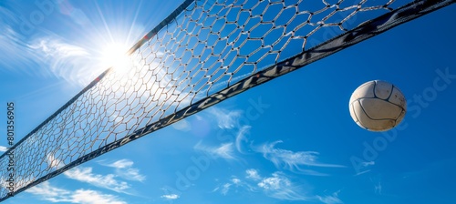 Beach volleyball ball and net under blue sky, symbolizing summer relaxation and coastal sports