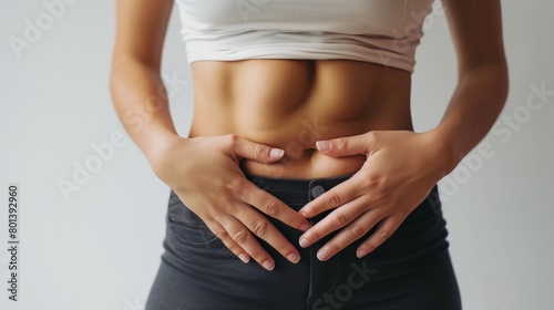 Close-up of a slender woman's torso showing her toned abdomen with hands placed on hips.