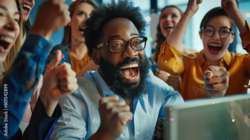 An emotional portrait of a group of office workers who are happy about completing a deal. People look at the computer screen, rejoice and have a great time
